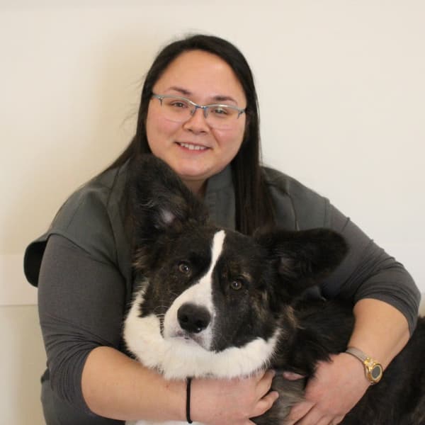 Dr. Melissa Watts, Veterinarian, holding her black and white dog.